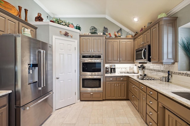 kitchen featuring light stone countertops, appliances with stainless steel finishes, lofted ceiling, and backsplash