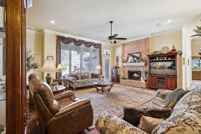 living room featuring hardwood / wood-style flooring, crown molding, ceiling fan, and a fireplace