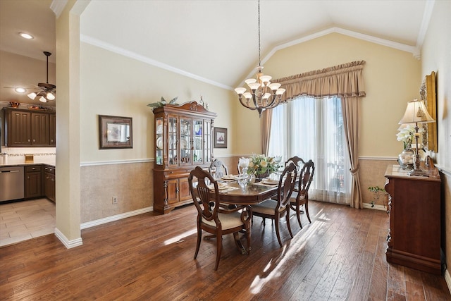 dining space featuring vaulted ceiling, ornamental molding, ceiling fan with notable chandelier, and hardwood / wood-style floors