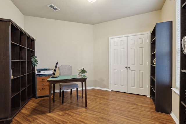 home office featuring dark wood-type flooring, visible vents, and baseboards