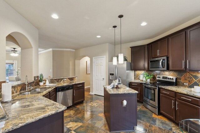 kitchen featuring hanging light fixtures, appliances with stainless steel finishes, kitchen peninsula, a kitchen island, and backsplash