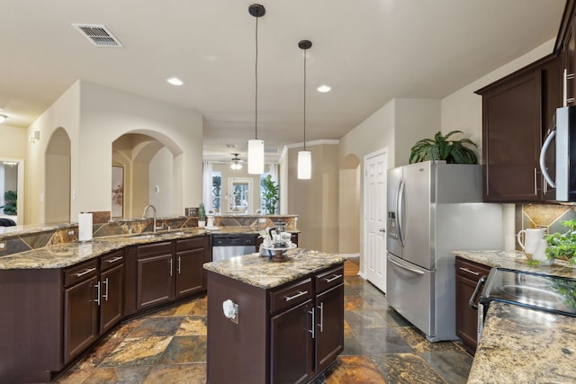 kitchen with visible vents, decorative backsplash, a center island, stone finish flooring, and stainless steel appliances