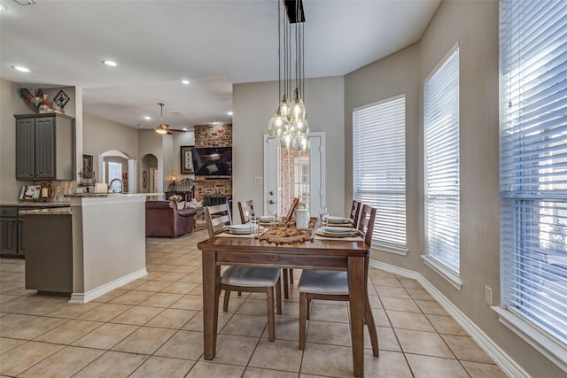 tiled dining space featuring ceiling fan and a fireplace