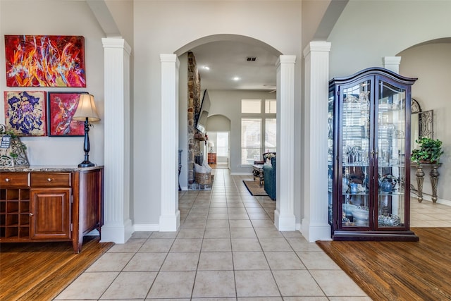 corridor featuring light tile patterned flooring and ornate columns