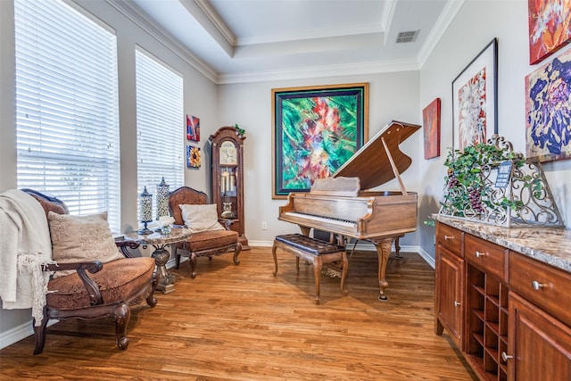 sitting room with a raised ceiling, crown molding, and light hardwood / wood-style flooring