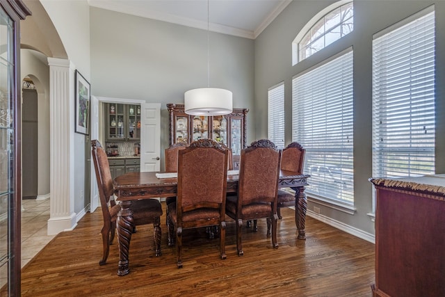 dining area featuring hardwood / wood-style floors, crown molding, plenty of natural light, and a towering ceiling