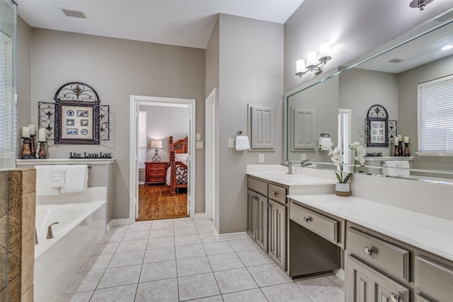 bathroom featuring a relaxing tiled tub, tile patterned floors, and vanity