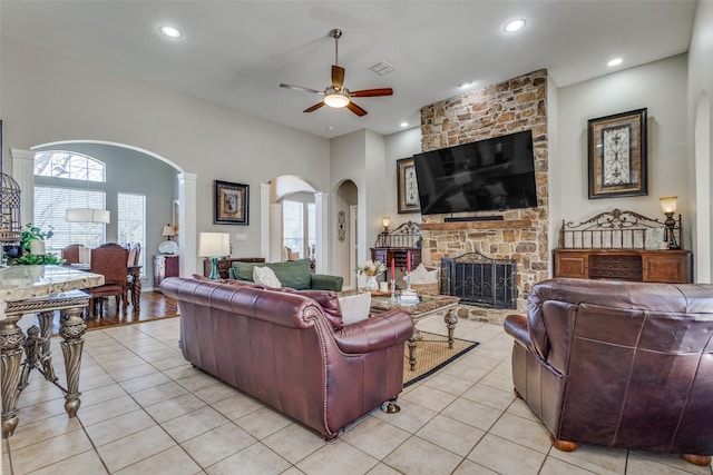 living room featuring a fireplace, ceiling fan, and light tile patterned flooring