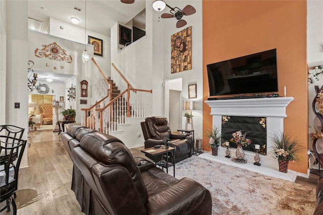 living room with light hardwood / wood-style flooring, ceiling fan, and a high ceiling