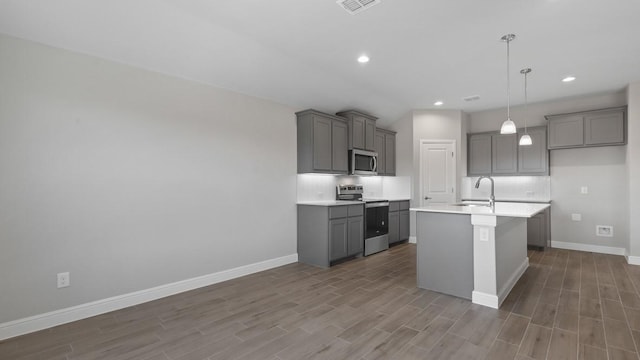 kitchen featuring sink, gray cabinetry, decorative backsplash, a kitchen island with sink, and stainless steel appliances