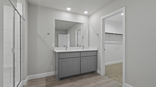 bathroom featuring a shower with door and vanity