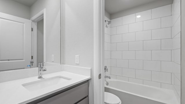 full bathroom with tiled shower / bath, vanity, and toilet