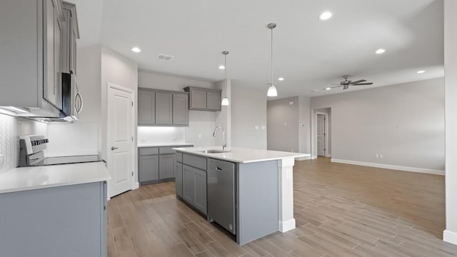 kitchen with gray cabinets, appliances with stainless steel finishes, sink, and a center island with sink