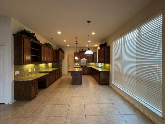 kitchen featuring pendant lighting, dark brown cabinetry, a center island, and light tile patterned floors