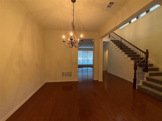 unfurnished dining area with ornamental molding, dark wood-type flooring, and a chandelier