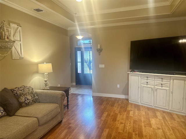 living room featuring ornamental molding, a raised ceiling, and light wood-type flooring