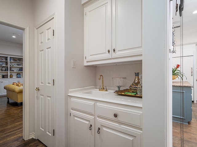 bar featuring ornamental molding, dark hardwood / wood-style flooring, sink, and white cabinets