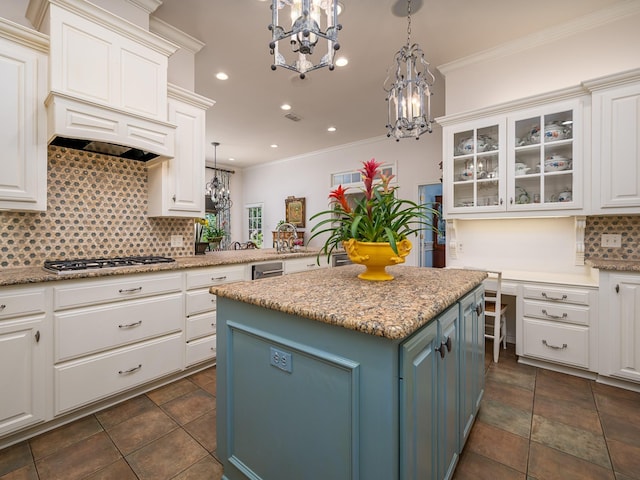 kitchen featuring pendant lighting, blue cabinetry, a center island, ornamental molding, and stainless steel gas cooktop