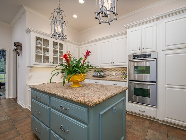 kitchen with a kitchen island, double oven, white cabinets, a chandelier, and hanging light fixtures