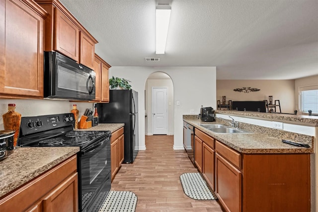 kitchen with sink, light hardwood / wood-style flooring, black appliances, and a textured ceiling