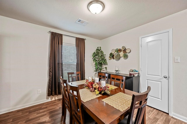 dining area with hardwood / wood-style flooring and a textured ceiling