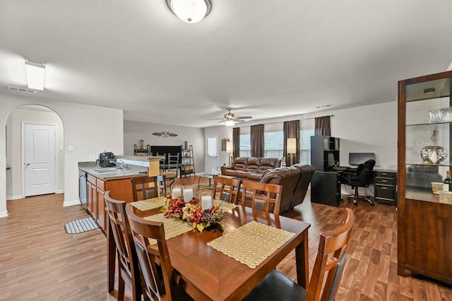 dining space with sink, ceiling fan, and light wood-type flooring