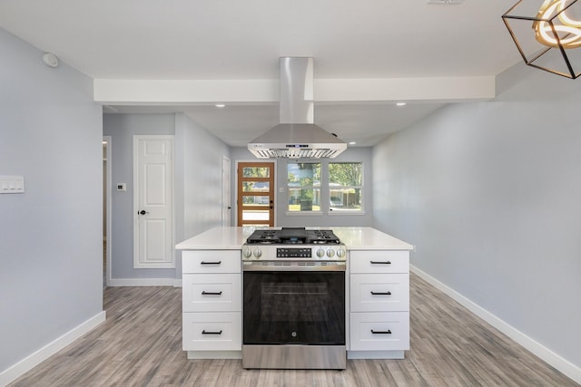 kitchen with stainless steel gas stove, island range hood, white cabinetry, and light wood-type flooring