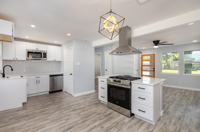 kitchen featuring white cabinetry, island range hood, decorative light fixtures, and appliances with stainless steel finishes