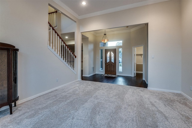 entryway featuring baseboards, a towering ceiling, stairway, ornamental molding, and dark colored carpet