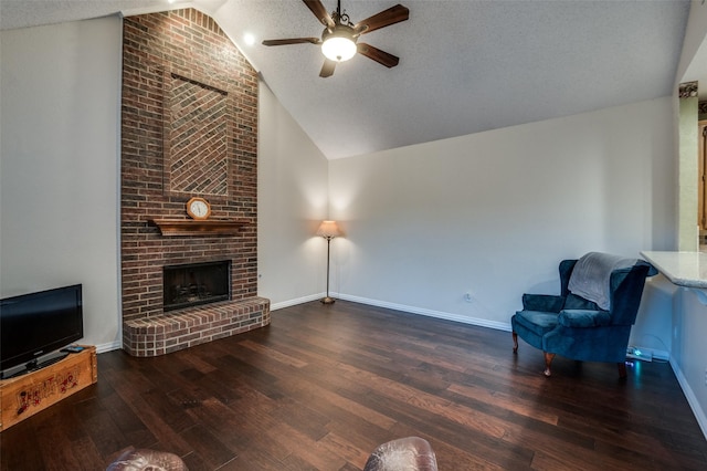 living area with dark wood-type flooring, a ceiling fan, a brick fireplace, a textured ceiling, and baseboards