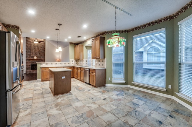 kitchen featuring a fireplace, light countertops, appliances with stainless steel finishes, a center island, and pendant lighting