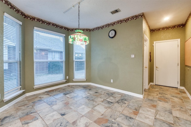 spare room with a textured ceiling, visible vents, and baseboards