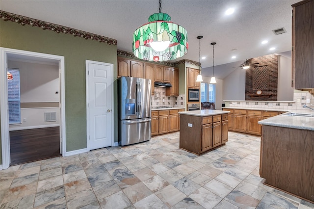 kitchen featuring visible vents, a kitchen island, decorative light fixtures, stainless steel appliances, and light countertops