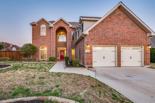 traditional home featuring driveway, a garage, fence, and brick siding