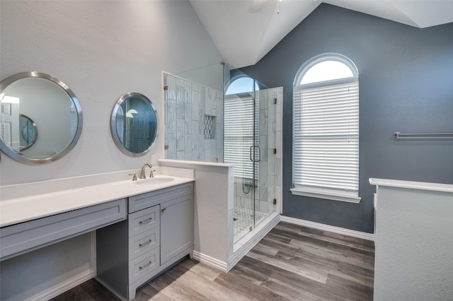 full bathroom featuring a ceiling fan, wood finished floors, vaulted ceiling, a tile shower, and vanity