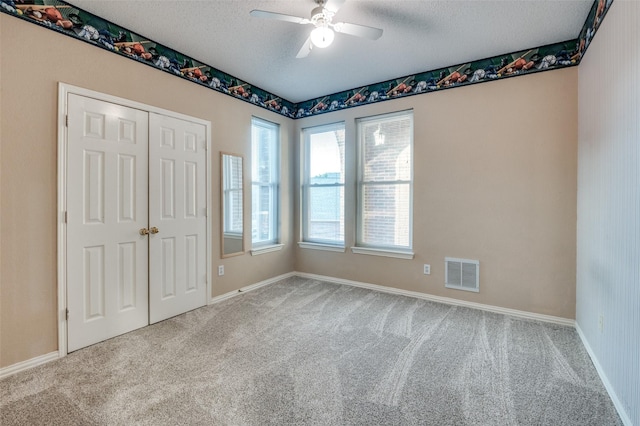 unfurnished room featuring baseboards, visible vents, light colored carpet, ceiling fan, and a textured ceiling