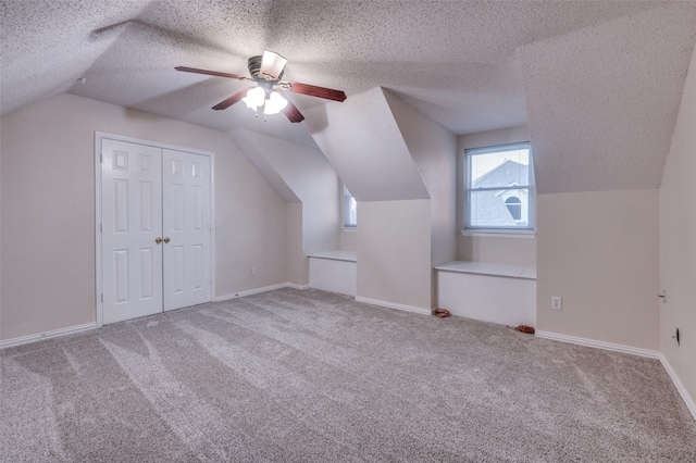 additional living space with a textured ceiling, lofted ceiling, a ceiling fan, baseboards, and carpet