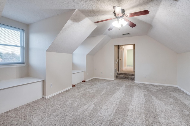 bonus room featuring a textured ceiling, vaulted ceiling, light carpet, and visible vents