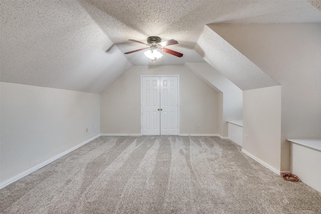 bonus room featuring a textured ceiling, vaulted ceiling, baseboards, and light colored carpet