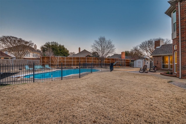 view of swimming pool featuring a fenced backyard, a storage shed, an outdoor structure, a yard, and a fenced in pool