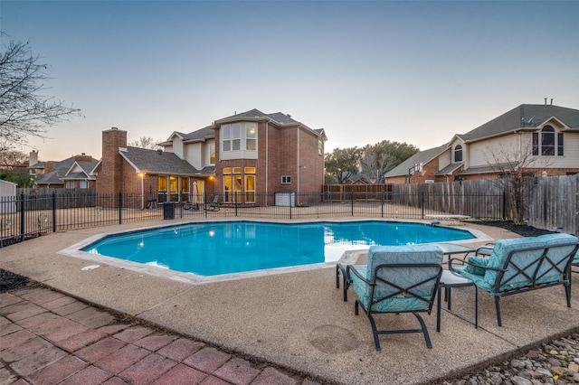 pool at dusk featuring a patio area, fence, and a fenced in pool