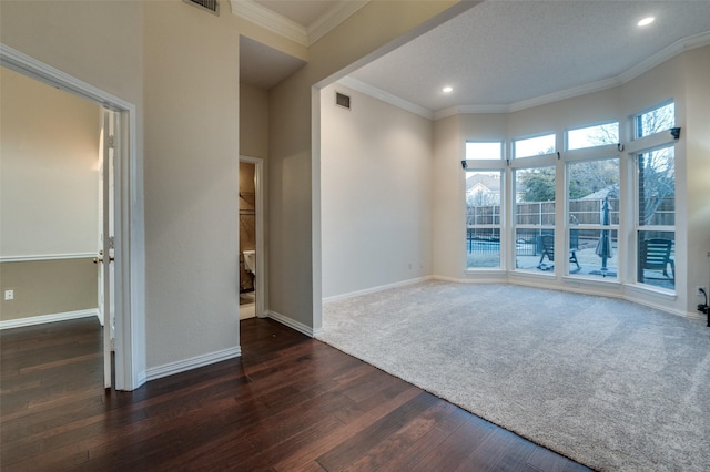 empty room with ornamental molding, visible vents, dark wood finished floors, and baseboards