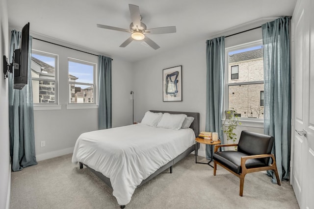 carpeted bedroom featuring ceiling fan and multiple windows