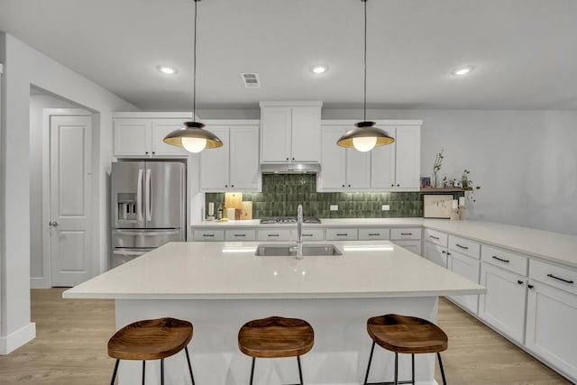 kitchen featuring hanging light fixtures, appliances with stainless steel finishes, sink, and a breakfast bar area