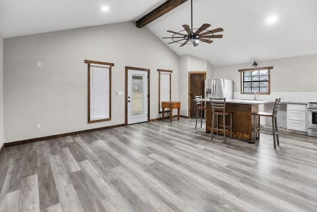 interior space with sink, high vaulted ceiling, light wood-type flooring, ceiling fan, and beam ceiling