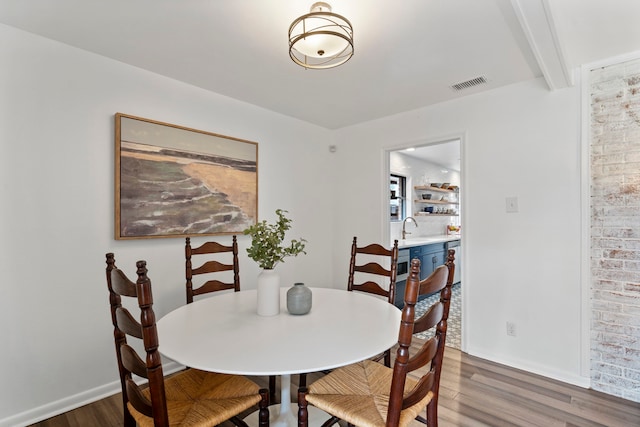 dining room with dark hardwood / wood-style flooring, sink, and beam ceiling