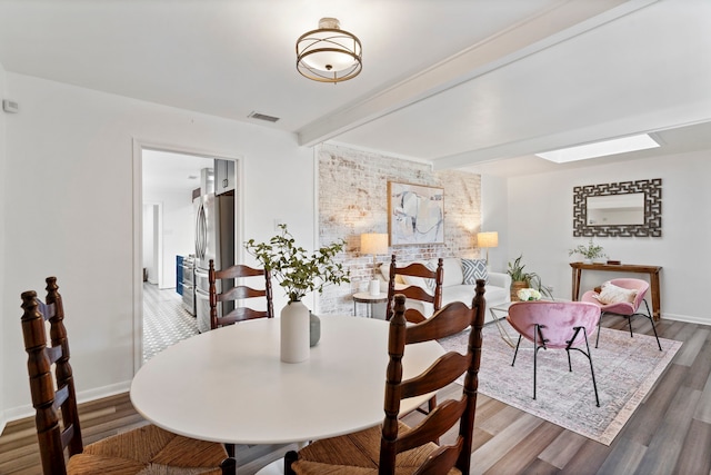 dining area with beam ceiling and hardwood / wood-style floors