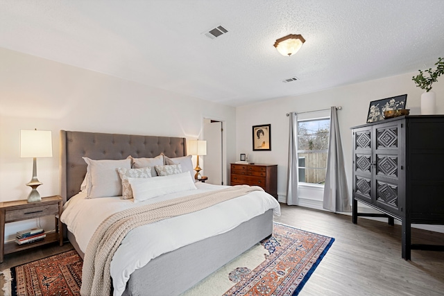 bedroom with hardwood / wood-style floors and a textured ceiling