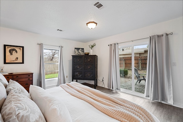 bedroom featuring hardwood / wood-style flooring, a textured ceiling, and access to outside