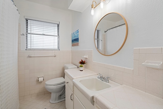 bathroom with tile walls, vanity, toilet, tile patterned floors, and a shower with curtain